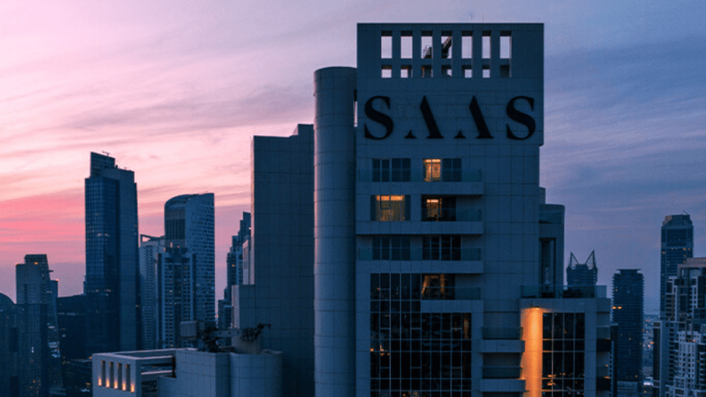 The towering SAAS Business Bay building at dusk, with the DAEM CONTRACTING LLC logo illuminated at the top, symbolizing the company's commitment to fire safety and protection